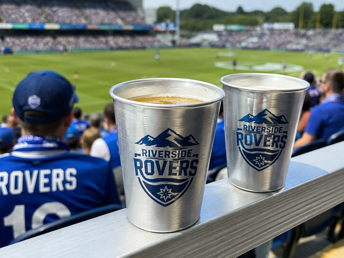 Wrap-printed recyclable aluminum cups on a stadium concourse with an invented sponsor brand